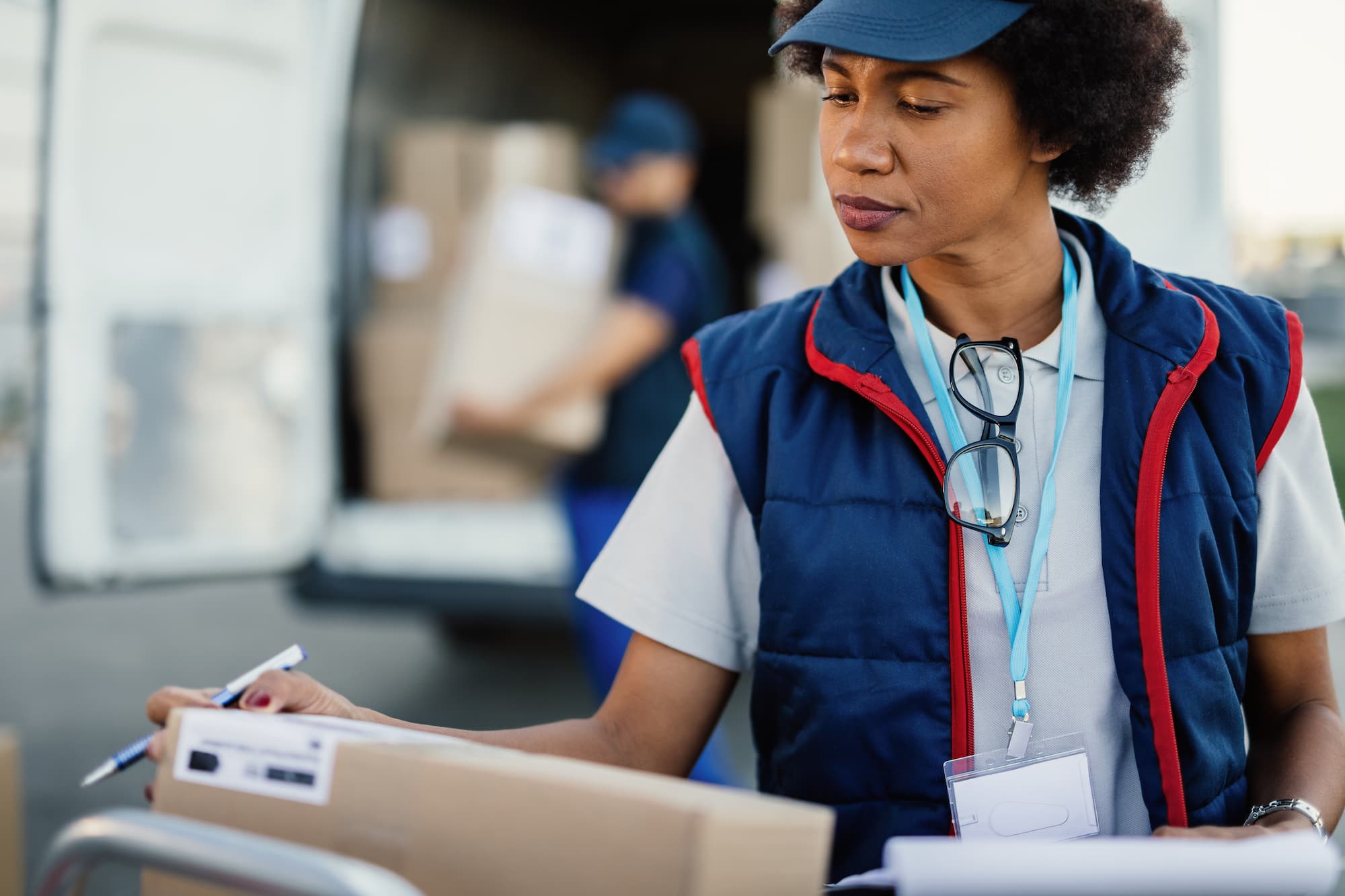 A postal worker inspects a package to verify the delivery address.