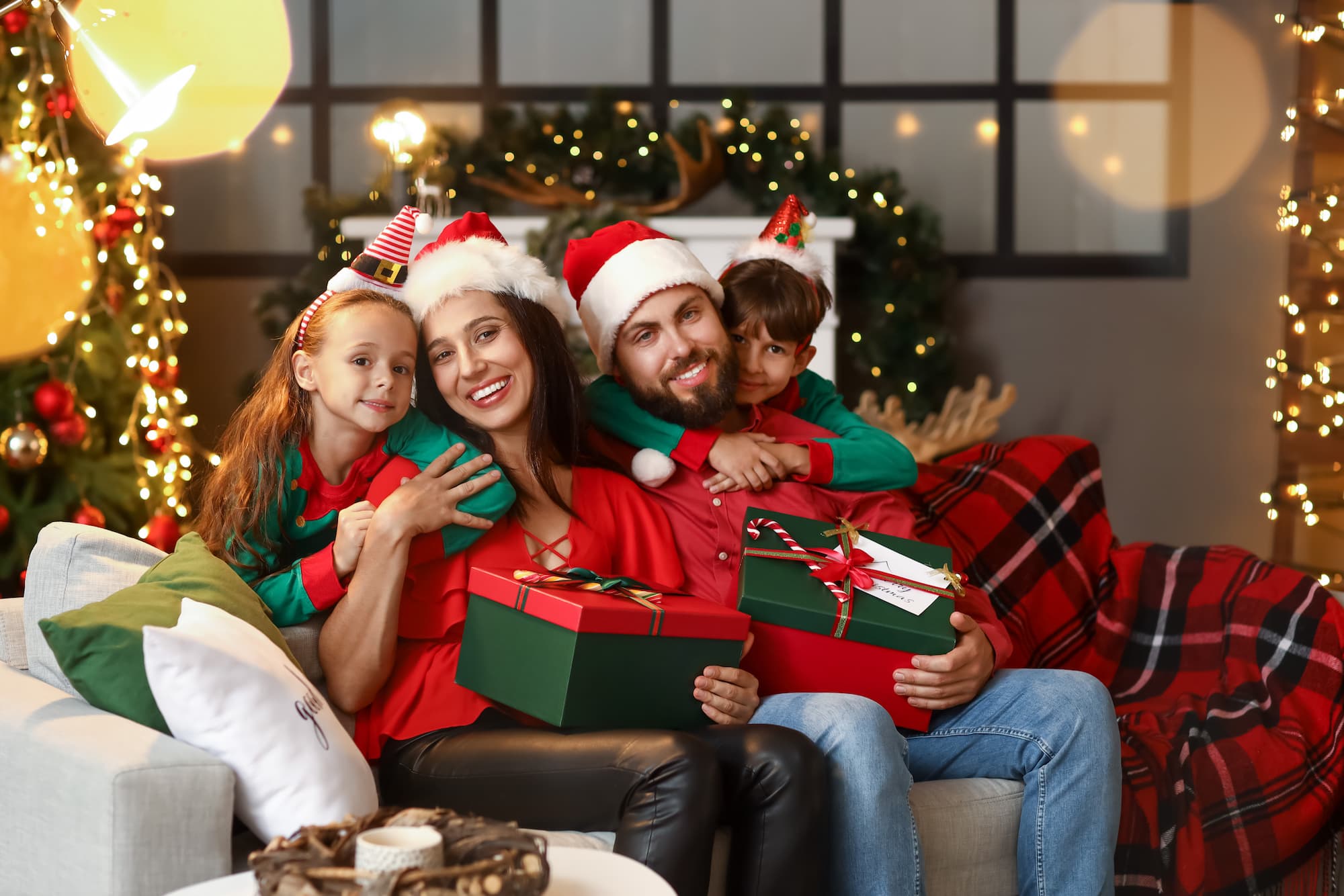 A family sits together on a sofa, smiling for a Christmas portrait.
